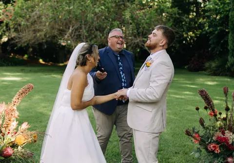 Josh Withers celebrating with a newly married couple during their outdoor wedding ceremony.